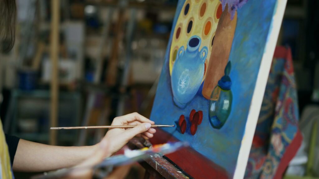 L'école d'Art's Close up of artist's hand painting a still life on canvas in a studio environment.