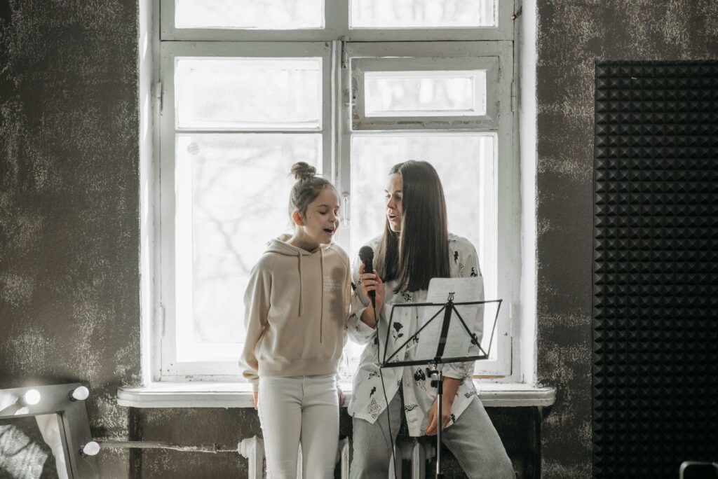 L'école d'Art's A young girl and her teacher practicing singing in a music studio.